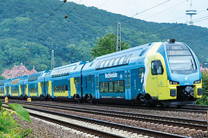 Der Elektrische Doppelstocktriebzug KISS der WestfalenBahn fährt auf Gleisen entlang. Im Hintergrund sind Bäume.